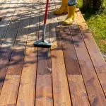 Applying deck stain to a wood deck, a process affected by humidity in Jacksonville Beach's coastal climate.
