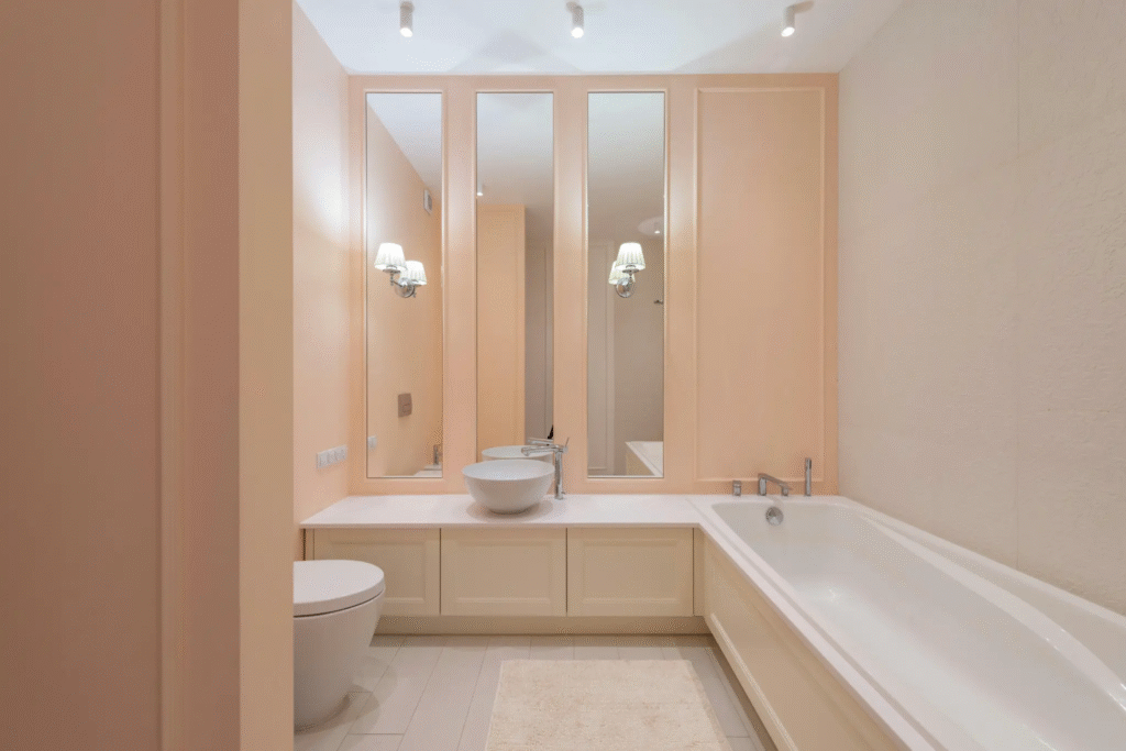 A charming bathroom with peach walls and a unique vanity. Painting shower fixtures can update any bathroom's aesthetic.
