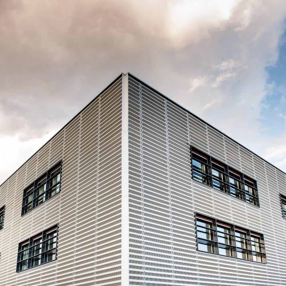 Professional commercial exterior painting in Jacksonville Beach, featuring a modern commercial building with clean geometric lines, large windows, and sleek siding under a clear blue sky.