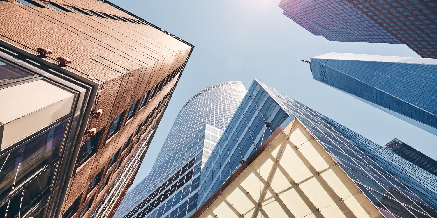 Commercial property painting in Jacksonville Beach, featuring modern commercial high-rise buildings with reflective glass and steel framing against a clear blue sky.